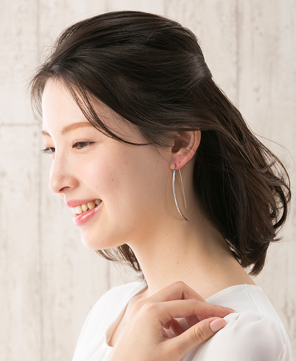 シャトンブランのイアリングをつけ笑顔で笑っている女性の横顔の写真